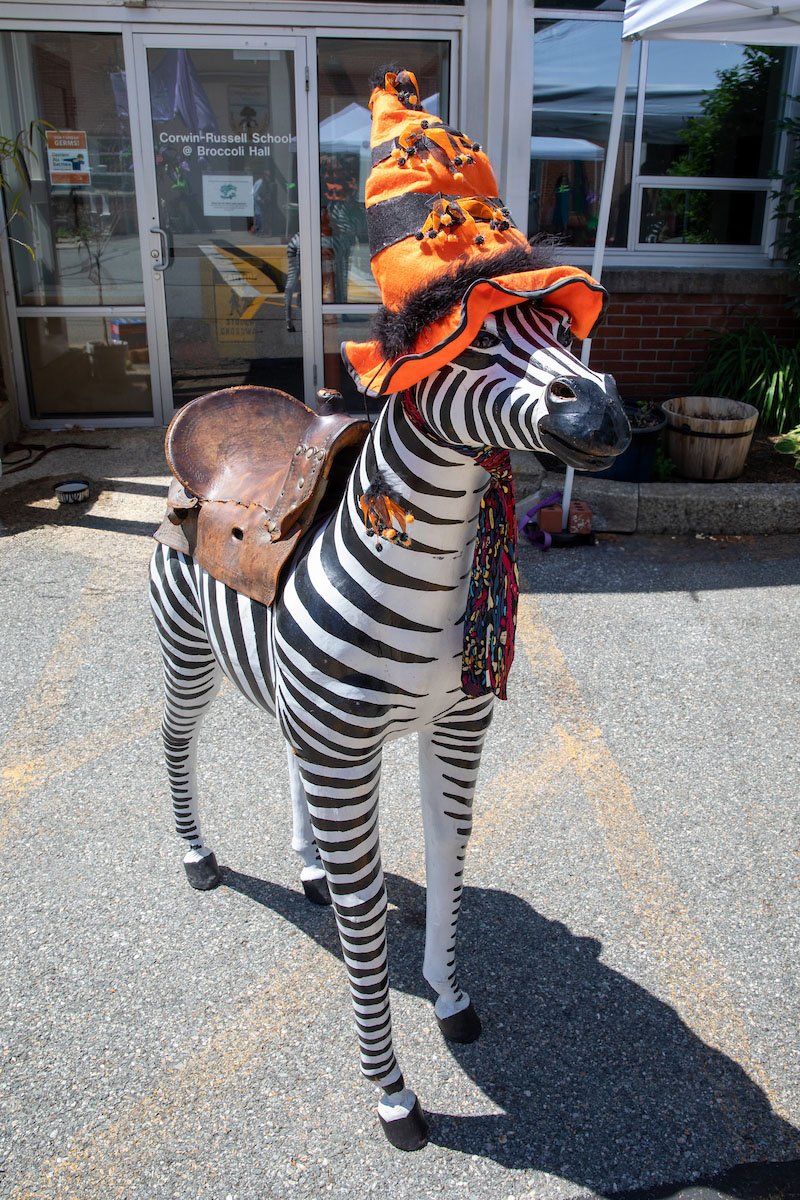 Zebra statue with saddle wearing orange and black pointed hat