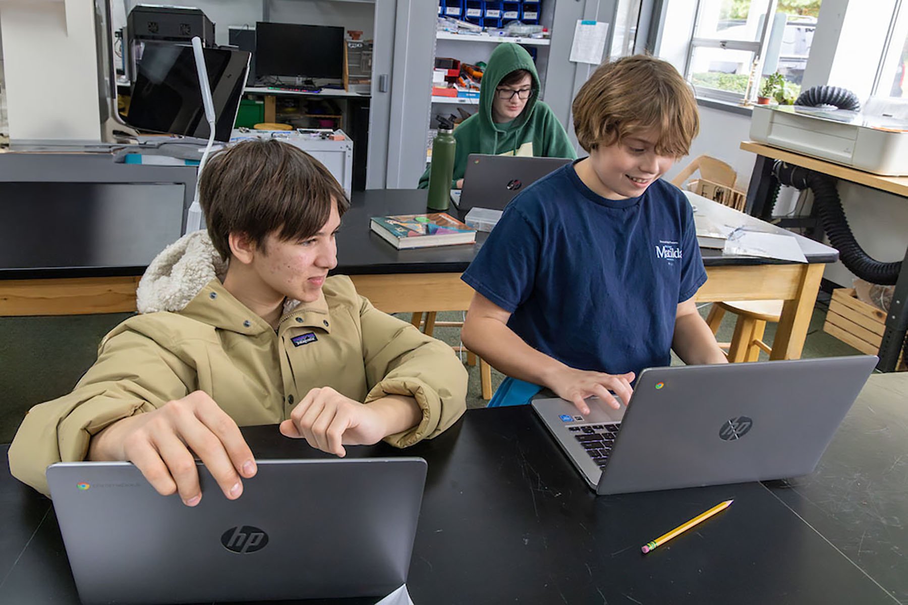 three students working in the science lab with computers