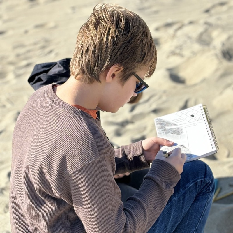 student drawing on the beach