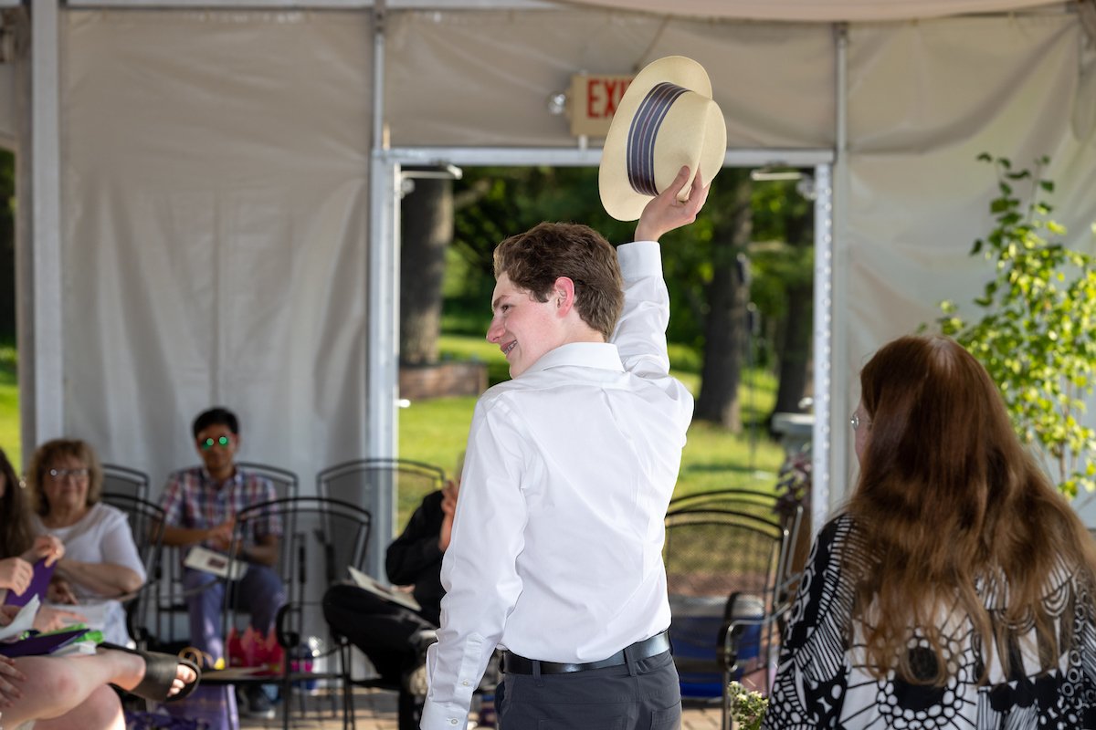 Student waving with straw hat