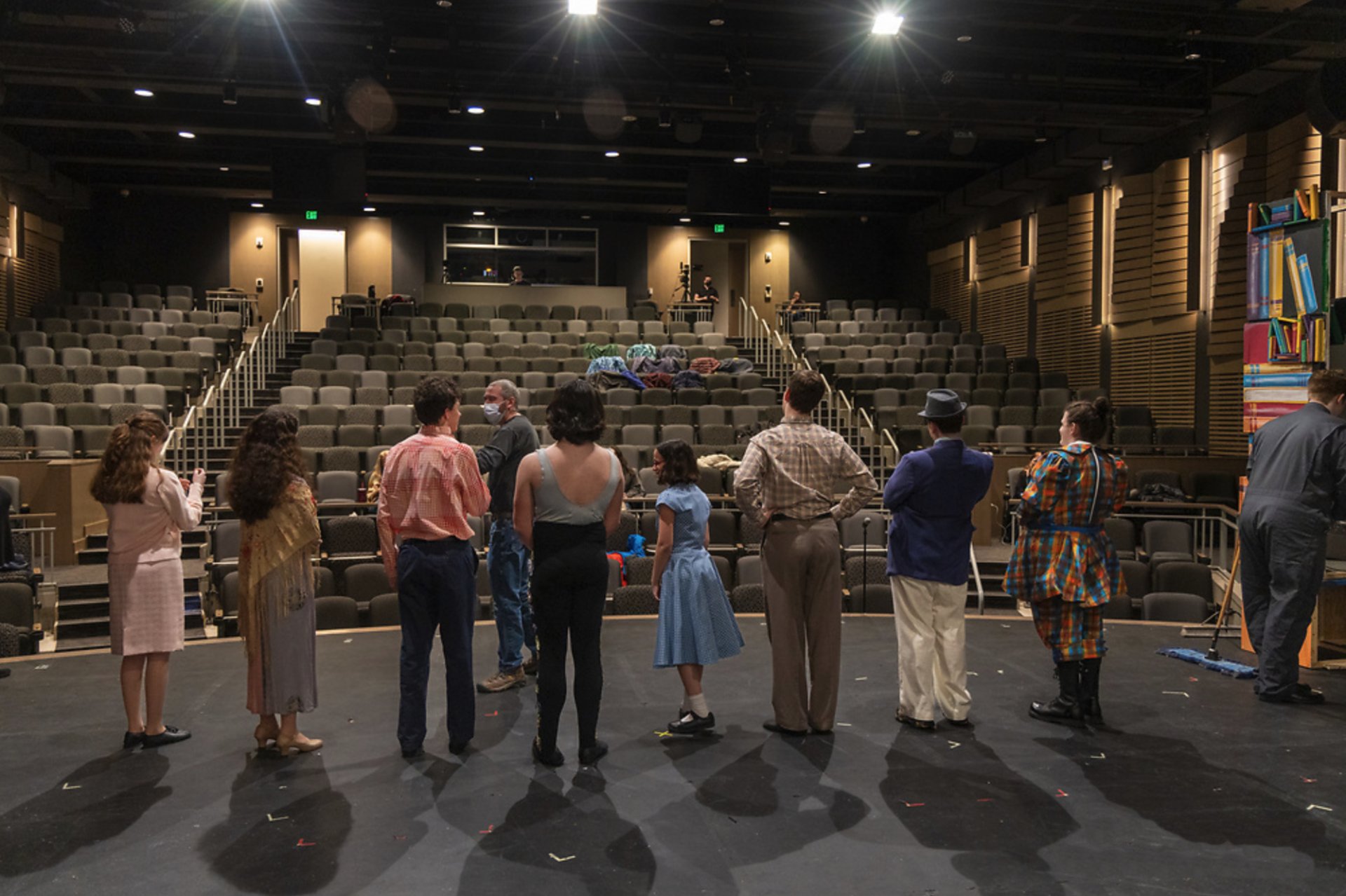 View of audience seating behind actors rehearing on stage