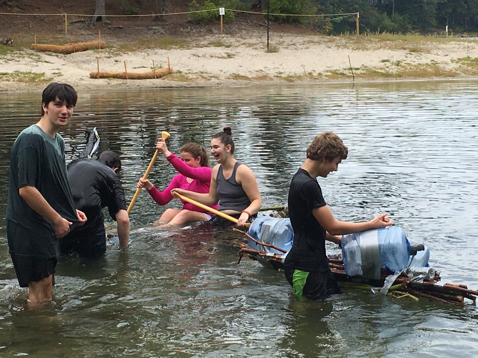 Students in lake on homemade raft made of recycled bottles